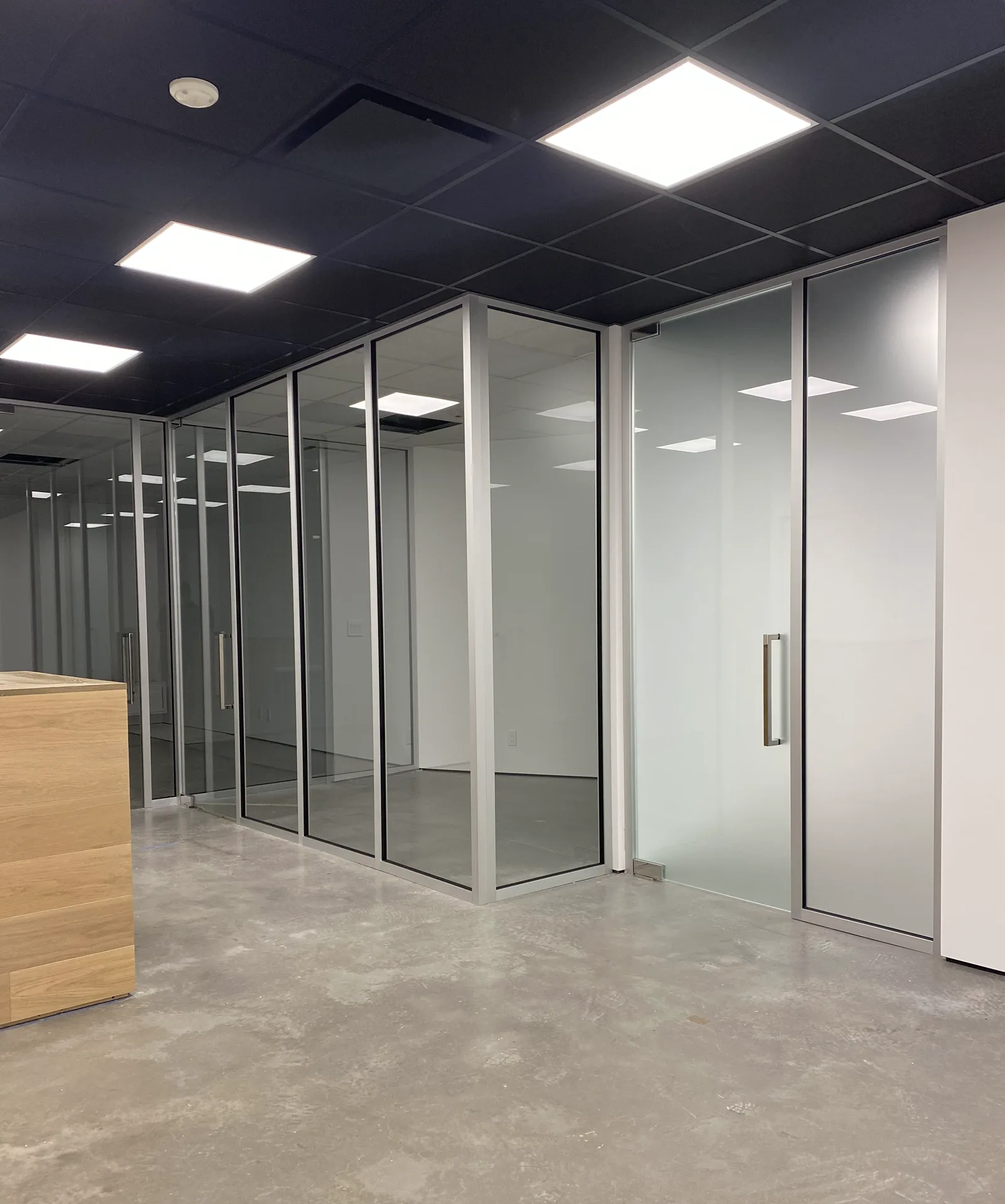 Gridless glass office partition with frosted privacy panel by WiseGlass NY