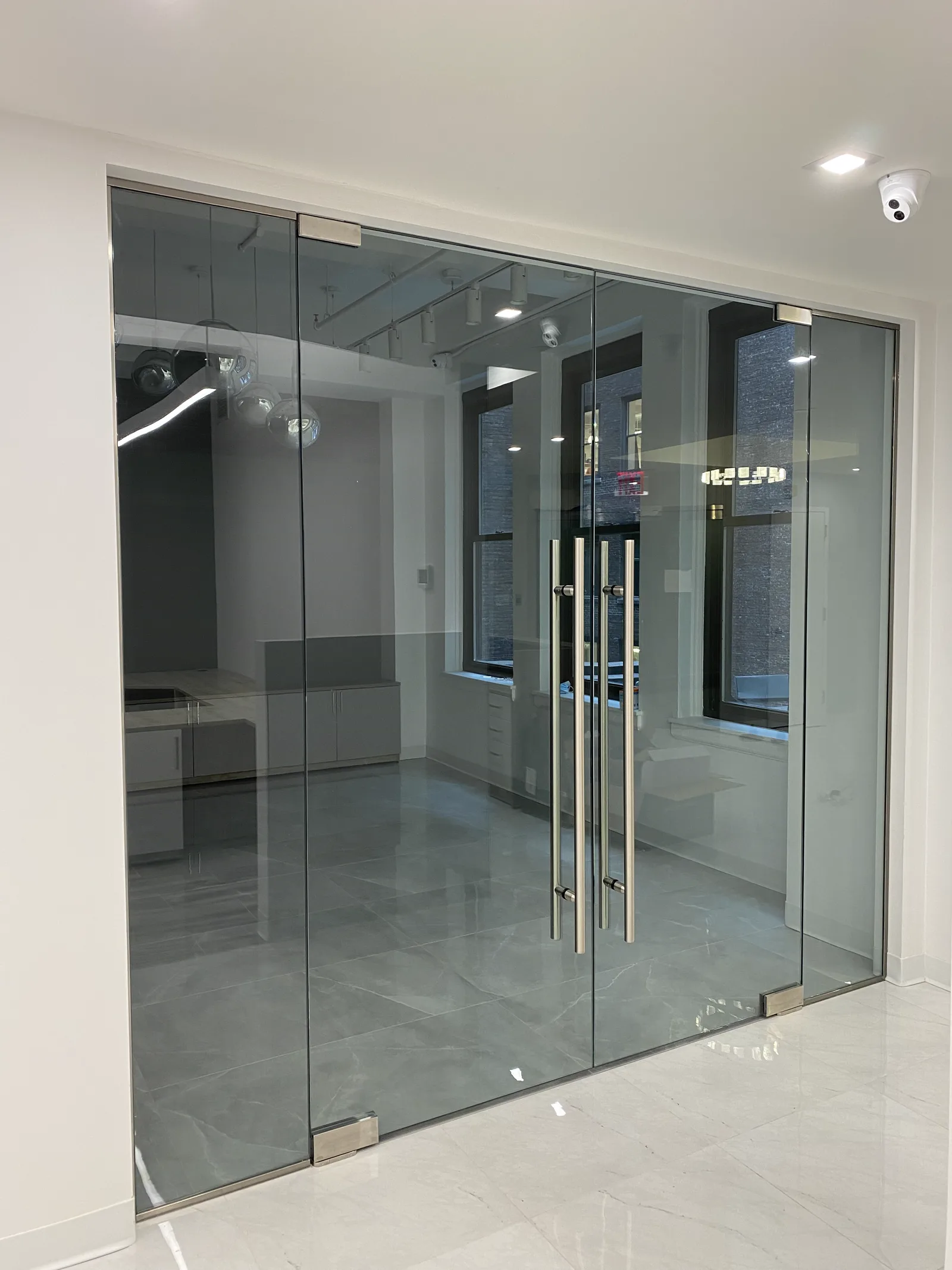 Frameless glass partition with tubular pull handles by WiseGlass NY