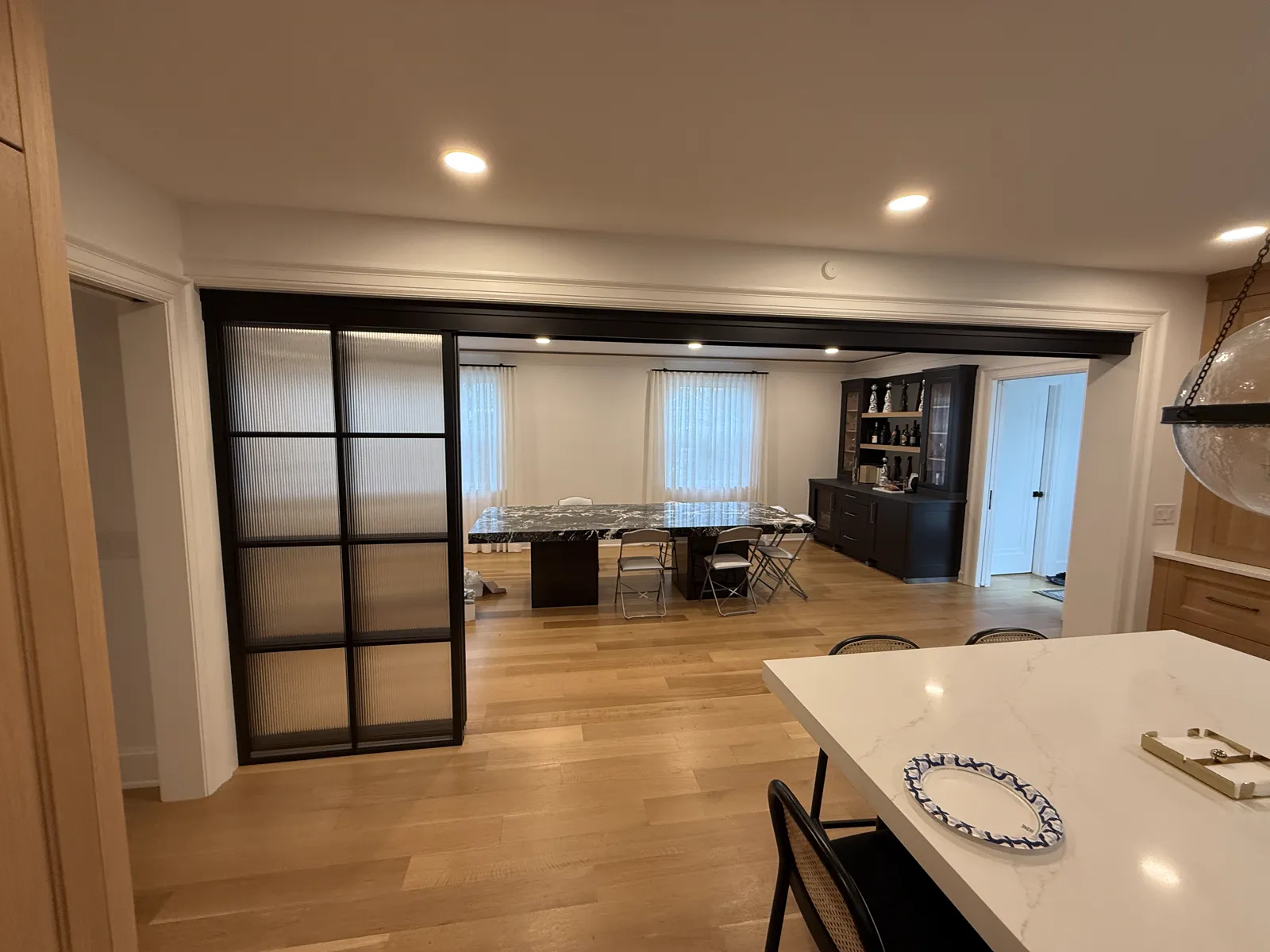 Telescopic reeded glass sliding panels stacked to one side of a wide opening between a kitchen and dining room, Allenhurst NJ by WiseGlass NY