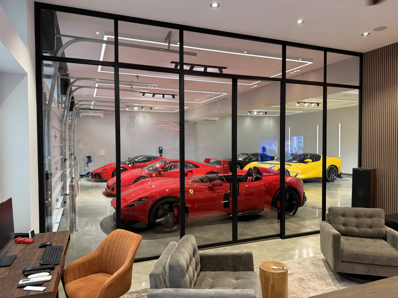 Custom black matte glass partition separating luxury lounge from Ferrari collection — WiseGlass NY