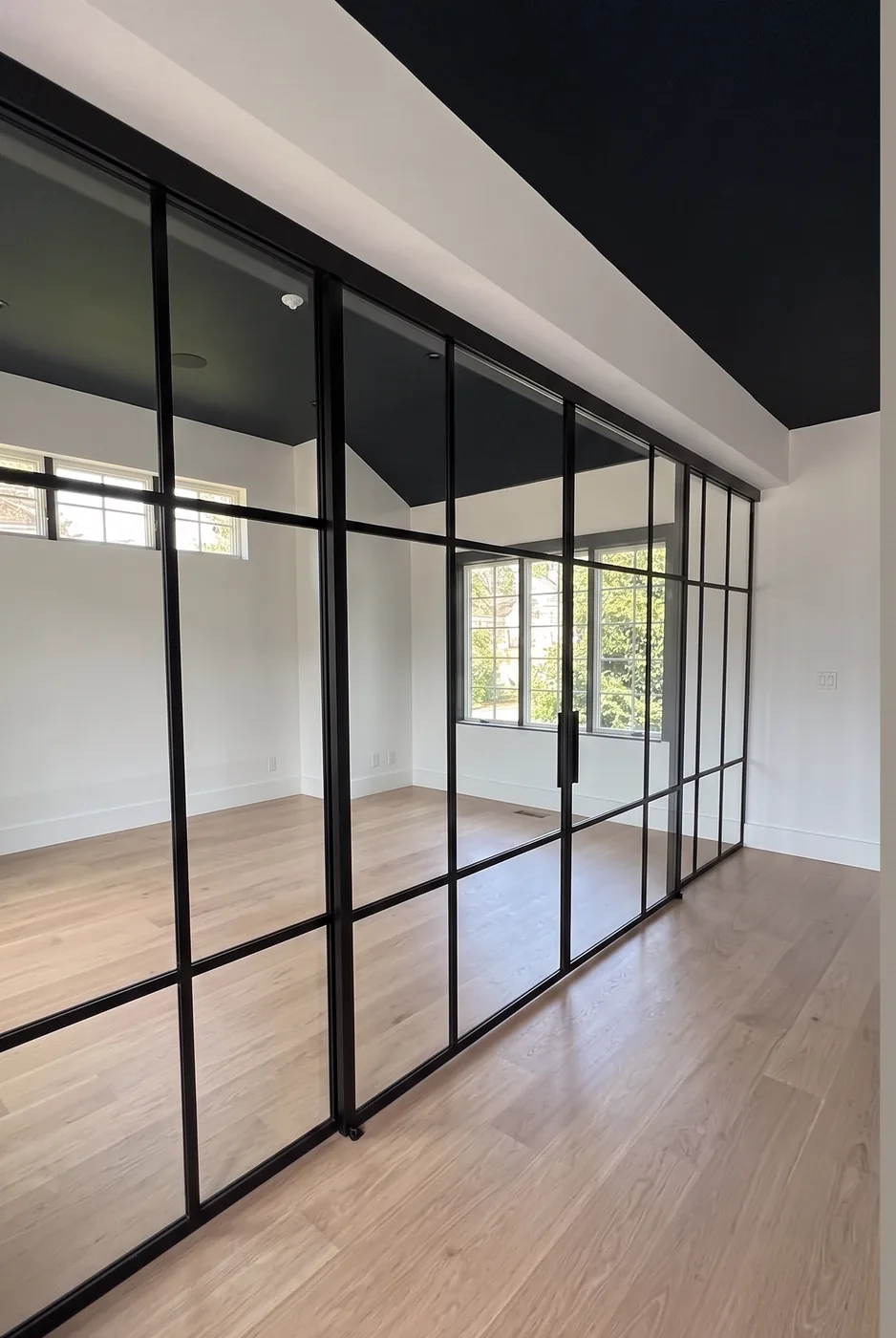 Head rail of a custom grid glass partition running along a dropped bulkhead beneath a raked ceiling, upstate New York by WiseGlass NY