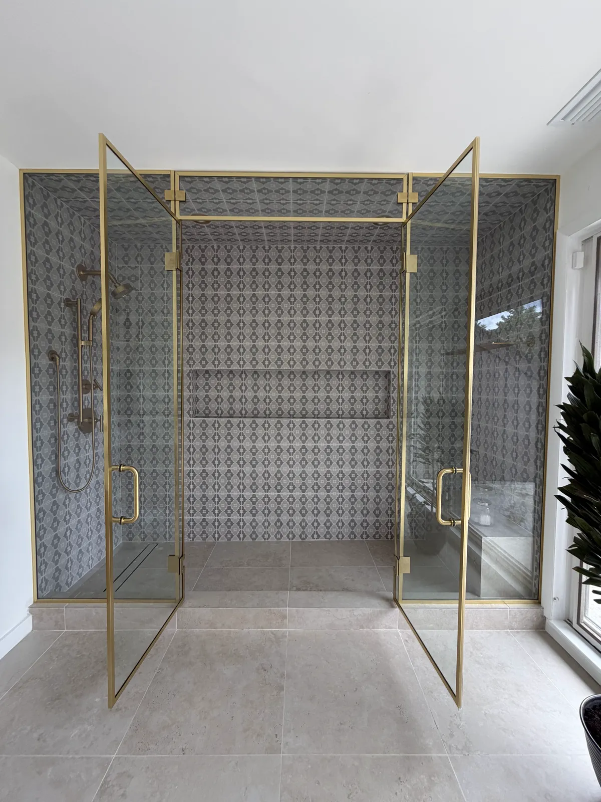 Brass-framed glass French shower doors swung fully open beneath a glass transom, West Orange NJ by WiseGlass NY