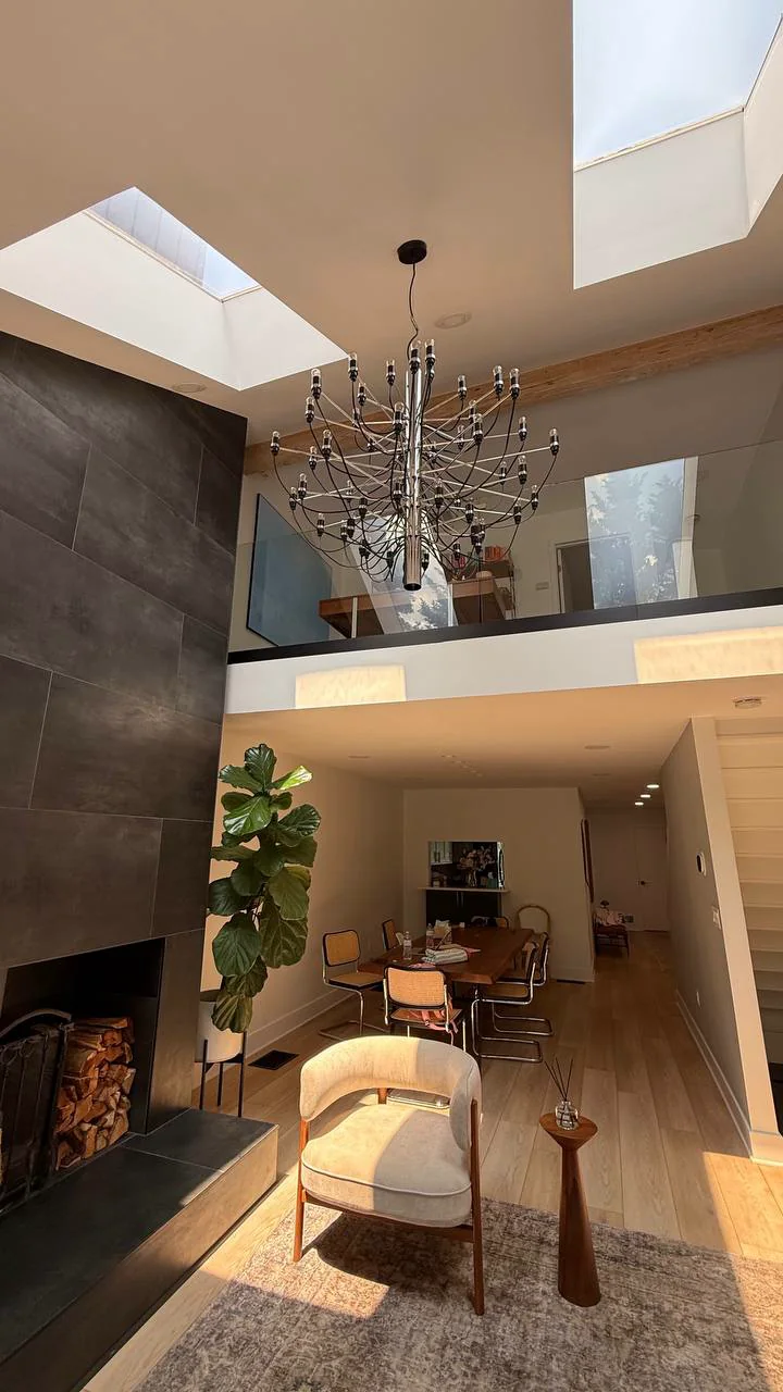 Frameless glass mezzanine railing above a double-height skylit living room in a New York City home by WiseGlass NY