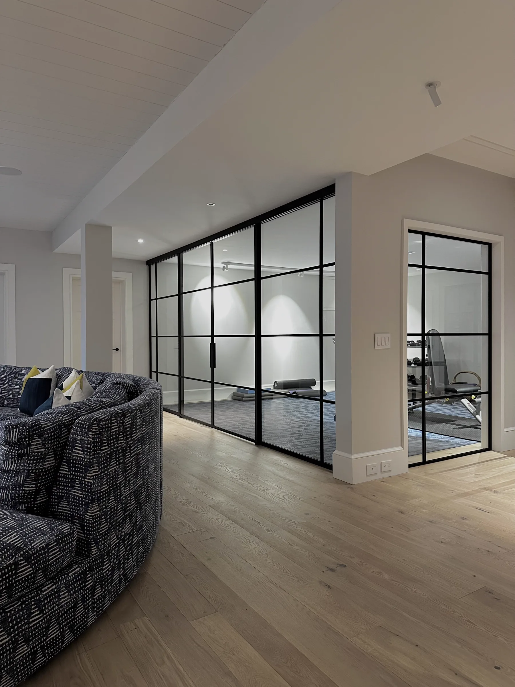 Custom double sliding glass partition installed in a residential gym, Sagaponack NY by WiseGlass NY