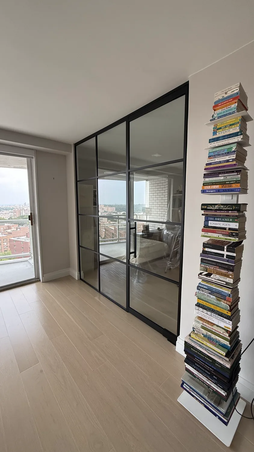 Glass partition wall with a single swing door carving a bedroom from an open plan New York City apartment by WiseGlass NY