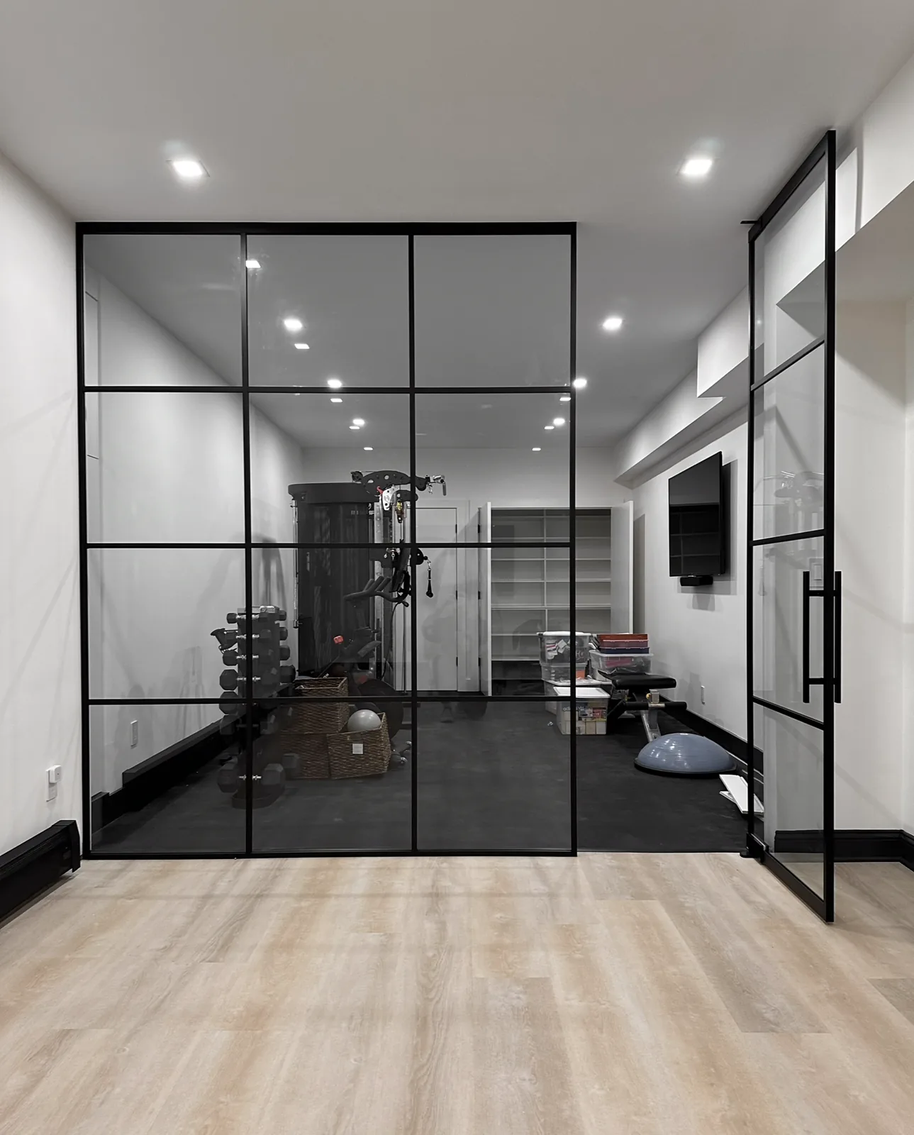 Tall glass partition with single swing door at gym entrance by WiseGlass NY